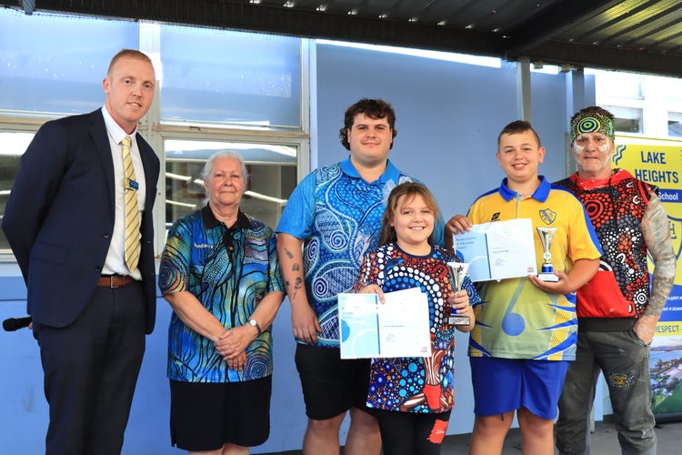 A principal standing with students and community members at an awards ceremony.
